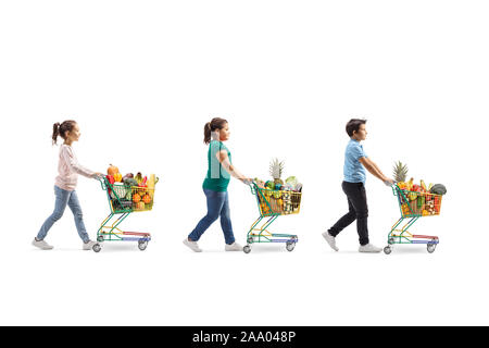 Profil de pleine longueur de balle trois enfants avec des chariots pleins d'aliments sains waling conformément isolé sur fond blanc Banque D'Images