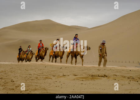 Tourisme chinois sur un tour de chameau dans le désert de dunes de sable chant Mingsha Banque D'Images