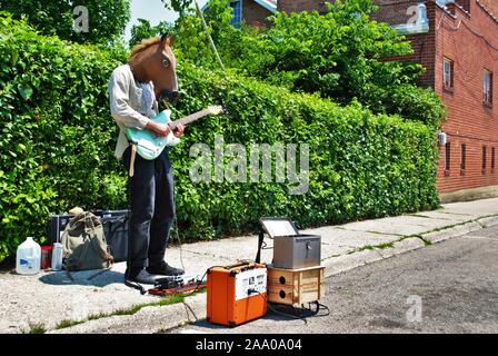 Artiste de rue jouant une guitare électrique tout en portant un masque de tête de cheval Banque D'Images