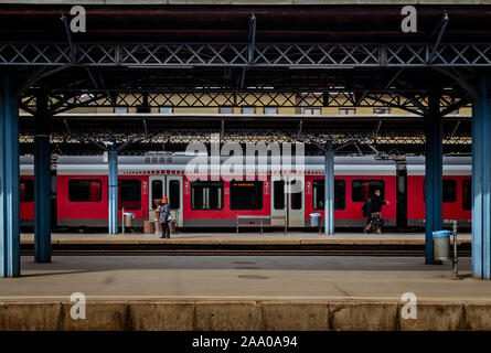 Signaleur et passagers sur un quai de gare de la gare Keleti de Budapest encadrée par des poteaux de plate-forme. Banque D'Images