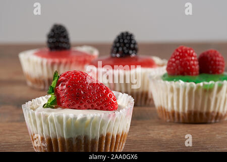 Crème glacée maison décorée avec des fraises, mûres, framboises, de la sauce aux kiwis et sauce aux fraises sur un fond de bois. Banque D'Images