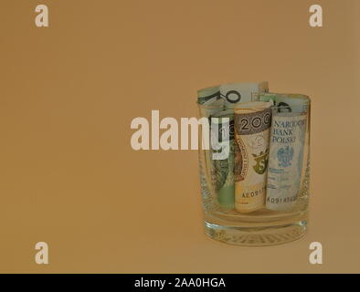 Billets de 200 et 100$ en rouleaux laminés à l'intérieur de près de verre isolé sur fond couleur pêche pastel. Banque D'Images