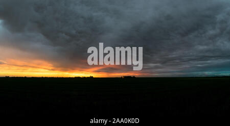 Ciel dramatique sur le paysage hollandais après le coucher du soleil. De belles couleurs et textures dans le ciel. Ferme lointain est éclairé par les derniers rayons du soleil. Banque D'Images