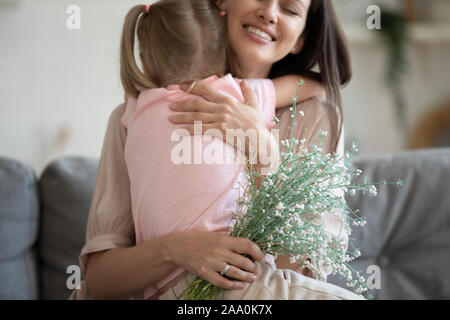 Image recadrée l'accent sur les fleurs, heureux jeune mère de câliner sa fille. Banque D'Images