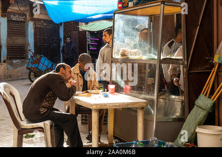 Fes, Maroc. Le 9 novembre 2019. Deux hommes mangent sur une table dans la rue Banque D'Images