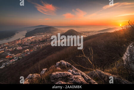 Vue d'une petite ville près de Danube au lever du soleil. Hainburg an der Donau, Autriche vu de Hundsheimer avec Rocky Hill Premier plan. Banque D'Images