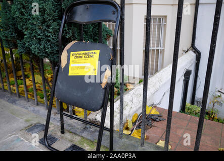 Chaise brisée en caoutchouc laissée non collectée sur le trottoir avec l'étiquette jaune « Environmental crime Scene » du quartier de Kensington et Chelsea, Banque D'Images