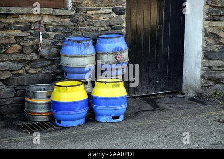 Keswick, Cumbria, Royaume-Uni - le 6 avril 2019 : bleu et jaune des tonnelets de bière empilées contre un mur de pierre à l'extérieur d'un pub en Angleterre Banque D'Images