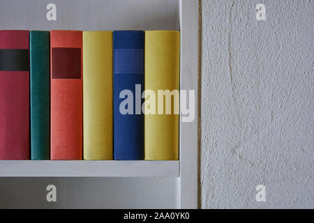 Close up of livres colorés dans une étagère de mur blanc Banque D'Images