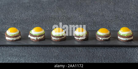 Canape avec fromage à la crème, guacamole et oeufs de caille frit sur la plaque Banque D'Images