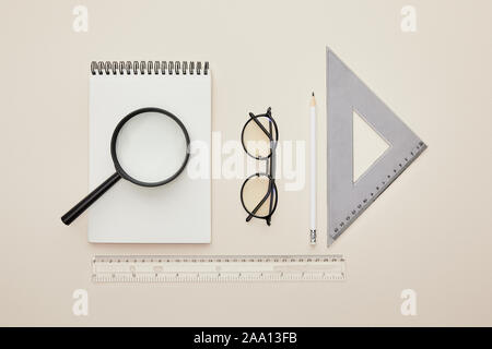 Vue de dessus de l'ordinateur portable sur loupe près de verres et les gouvernants sur rond isolé Banque D'Images