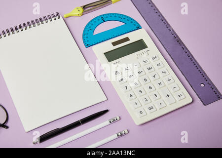 Calculatrice et bloc-notes et crayons avec près de pen isolé sur purple Banque D'Images