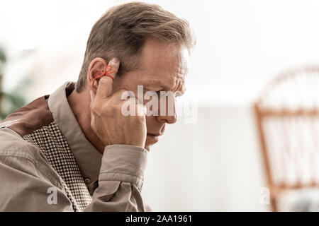 L'homme a pris sa retraite avec red bow on finger touching temple Banque D'Images