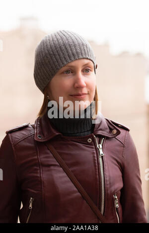 Fille dans la rue. Veste en cuir, col roulé gris et le chapeau. Banque D'Images