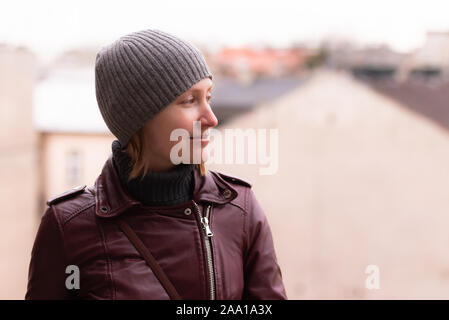 Fille dans la rue. Veste en cuir, col roulé gris et le chapeau. Regarde sur la droite. À la vers la gauche. Banque D'Images