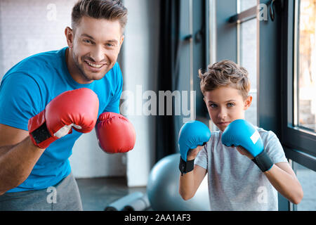 Heureux père et fils mignon in boxing gloves working out in gym Banque D'Images