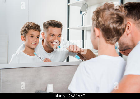 Portrait of happy kid et joyeux Père se brosser les dents dans la salle de bains Banque D'Images