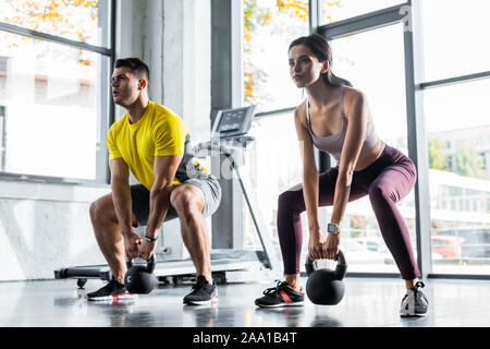 Sportif et de la sportive faisant squat avec haltères en sports centre Banque D'Images