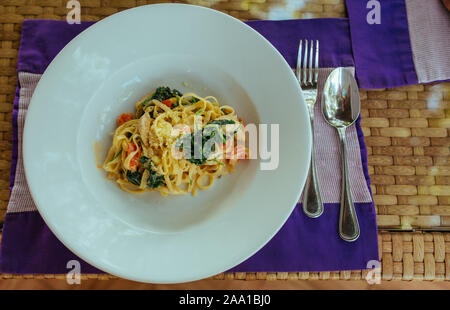 Carbonara faites maison sur plaque bleue avec cuillère et fourchette Banque D'Images