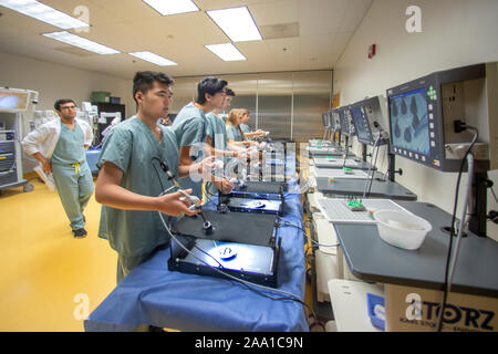 En regardant leurs progrès sur les moniteurs en été, pour un atelier de chirurgie, les adolescents des gommages médicaux télécommande pratique les techniques de chirurgie laproscopic sous un œil attentif du médecin dans un Orange, CA, de l'hôpital. Banque D'Images