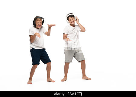 Deux frères gai écoute au casque de la musique et de la danse sur fond blanc Banque D'Images
