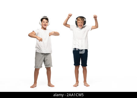Deux frères gai écoute au casque de la musique et de la danse sur fond blanc Banque D'Images
