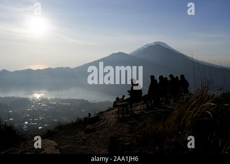 Bali, Indonésie. 18 Oct, 2019. La silhouette d'un groupe de randonneurs se détendre au sommet du Mont Batur à Bali durant le lever du soleil.Chaque jour des centaines de personnes l'ascension du Mont Batur pour voir le lever du soleil. Le mont Batur est un volcan actif situé dans l'île de Bali en Indonésie et sa dernière éruption a été enregistrée en 2000 et son plus haut sommet se trouve à 1717 mètres (5 633 pi) au-dessus du niveau de la mer où les gens peuvent avoir des vues à couper le souffle du Lac Batur, le Mont Abang et le Mont Agung. Lorsque le temps le permet, il est possible de voir le Mont Rinjani, un volcan actif sur l'île voisine de Lombok. C Banque D'Images