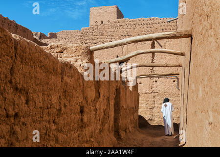 Habillés traditionnels homme marche à l'intérieur d'une Kasbah à M'hamid, Maroc. Banque D'Images