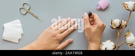 Mode accessoires manucure élégant avec des ciseaux à ongles, gel, poussoir de cuticle, coton, femmes et fleurs d'eucalyptus. Mise à plat, vue du dessus, Banque D'Images