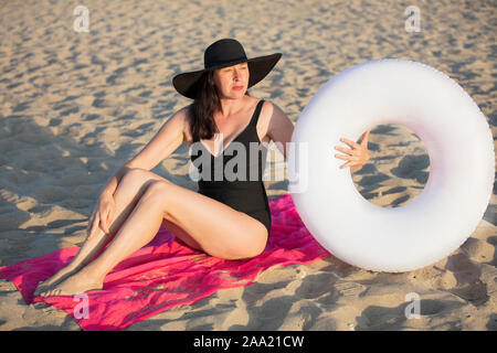 Femme âgée avec un cercle de natation sur la plage est au repos.Femme de soleil dans le sable.Maison de vacances à l'hôtel Banque D'Images