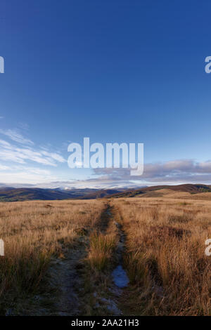 La route droite dans Glen Clova du sommet de Tulloch hill, à l'ouest vers la montagne enneigée du Cairngorms. Banque D'Images