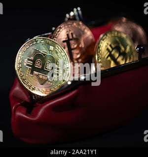 Or métallique des Bitcoins en portefeuille en cuir rouge sur fond noir Banque D'Images