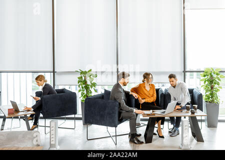 Jeune couple parlant avec le consultant financier au bureau de la banque mondiale de luxe. Concept d'investissement ou de prêt pour une jeune famille. Large vue avec grande fenêtre et copy space Banque D'Images