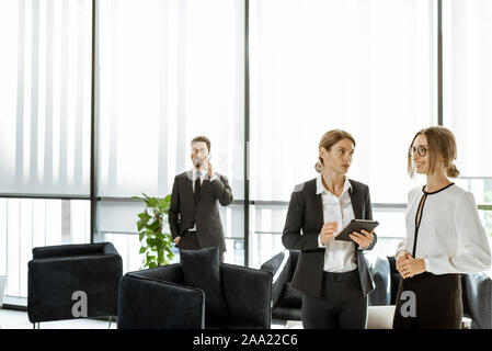 Les employés de l'institution financière ou d'autres grands copany ayant quelques affaires, debout et parler dans le bureau de luxe Banque D'Images