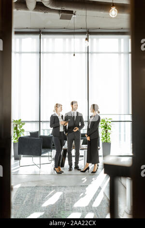 Les employés de l'institution financière, et dont certaines affaires, debout et parler dans le bureau de luxe. Voir à travers la porte Banque D'Images