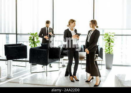 Les employés de l'institution financière ou d'autres grands copany ayant quelques affaires, debout et parler dans le bureau de luxe Banque D'Images