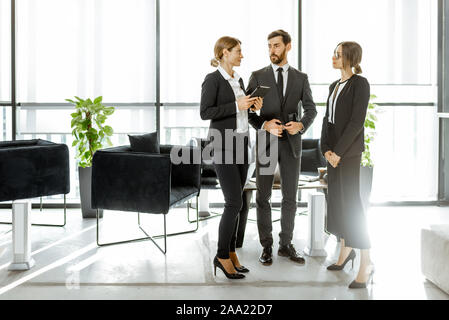 Les employés de l'institution financière ou d'autres grands copany ayant quelques affaires, debout et parler dans le bureau de luxe Banque D'Images