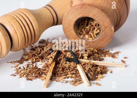 Close-up pipe en bois avec du tabac et d'allumettes brûlées sur un fond blanc Banque D'Images