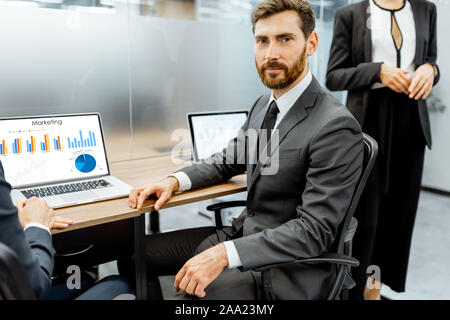 Portrait d'un homme employé en col blanc assis à la place de travail avec les ordinateurs portables de la société Banque D'Images
