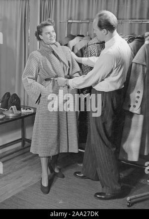 La mode féminine dans les années 40. Une jeune femme cherche un manteau à partir de l'automne 1949 à partir de la collection de la société Beves manteaux. Fashion designer Bengt Bunkstedt règle le détails. Suède 1949 Banque D'Images
