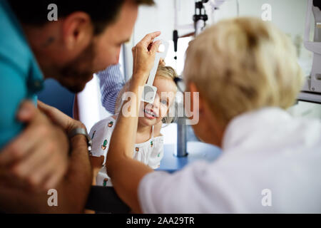 Contrôle de l'ophtalmologiste eye vision de peu de jolie fille dans une clinique moderne. Banque D'Images