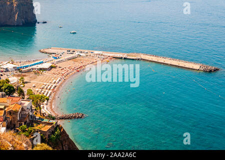 Vue de dessus sur les pierres rocheuses marinas sur la plage plein de touristes, de transats, parasols sur la mer Tyrrhénienne, près de la baie de Sorrente et méta villes en Na Banque D'Images