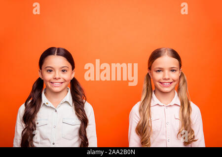 Portrait de deux jeunes enfants se tenant ensemble s'amuser le week-end sourire candide se sentir porter des vêtements de style décontracté sur fond de couleur orange isolé Banque D'Images