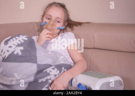 La petite fille ne l'inhalation à la maison.La jeune fille est assise à l'inhalation. L'enfant est malade et triste. La petite fille se sent mal. Banque D'Images