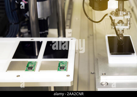 Bras de robot aspirateur automatique avec sucker travaillant dans la ligne de production et d'assemblage sur des écrans de smartphones et smartphone de haute technologie Banque D'Images