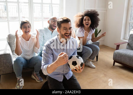 Jeune homme excité à lunettes préféré célébrer objectif de l'équipe. Banque D'Images