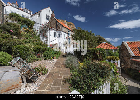 Chalets pittoresques et des jardins à Runswick Bay, North Yorkshire, North York Moors National Park, Angleterre, Royaume-Uni. Banque D'Images