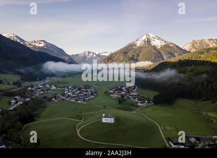 Vue aérienne, de l'église Sankt Anna et village avec brouillard tôt en face de Rofan, Achenkirch, Tyrol, Autriche Banque D'Images