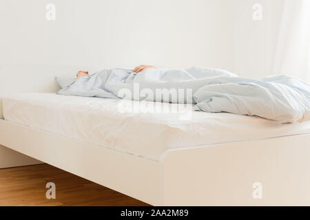 Partie de la maison ou de l'intérieur de l'hôtel, l'homme de dormir sur un lit blanc bleu avec linge de lit le matin Banque D'Images