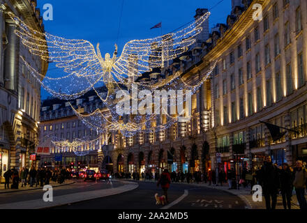 Les lumières de Noël des anges au-dessus de la rue Regent, le centre de Londres, avec des clients de vacances occupé, dans la soirée. Banque D'Images